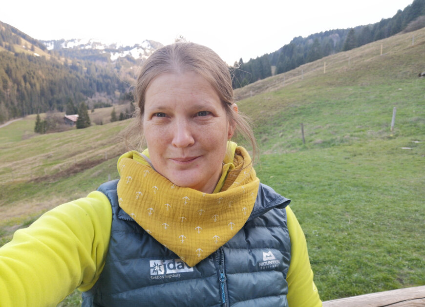 Eva Deibele, Leitung der Geschäftsstelle der DAV Sektion Augsburg steht bei der Otto-Schwegler-Hütte vor der Bergkulisse. Eva ist auch stellvertretende Leitung der Familienabteilung und Leiterin der Gruppe Bergfüchse. | © Eva Deibele